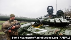 Украинский военнослужащий возле поврежденного российского танка. Донецкая область, Украина, 13 апреля 2022 года