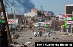 Мирные жители в белых простынях и с белыми флагами в руках, пересекают дорогу между Бучей и Ирпенем, 11 марта 2022 года.