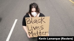 Удзельніца акцыі пратэсту з плякатам Black Lives Matter — «Жыцьці цемнаскурых маюць значэньне»