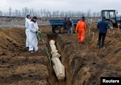 У Марыюпалі цягам году знайшлі ня менш як 10,3 тысячы магіл, якія зьявіліся пасьля пачатку расейскага ўварваньня ва Ўкраіну. У адной магіле можа быць пахавана па некалькі целаў. На фота, зробленым 4 лютага, — пахаваньне яшчэ ў адну масавую магілу пад Марыюпалем, у пасёлку Стары Крым, які кантралюе Расея