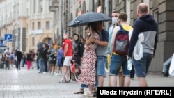 Людзі пад дажджом у шматкілямэтровым «ланцугу салідарнасьці» на праспэкце Незалежнасьці ў Менску ў дзень арышту Віктара Бабарыкі. 18 чэрвеня 2020